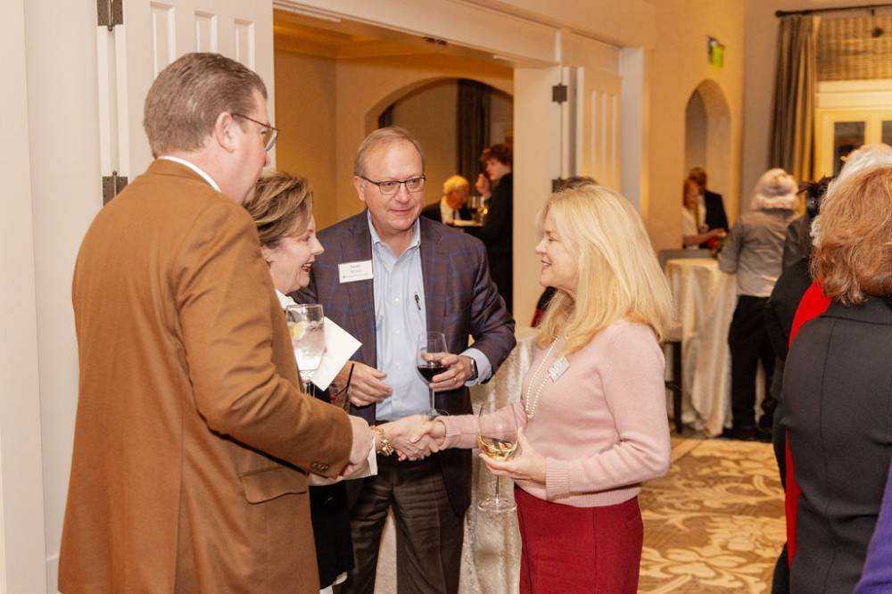 Four reception guests greeting each other, two of them shaking hands